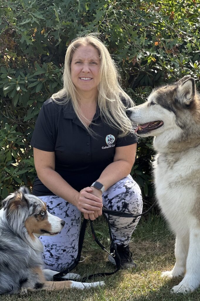 Trainer Jessica from The Cultured Canine kneels with two dogs